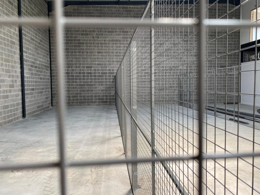 Détail d’une cloison grillagée installée pour délimiter des zones de stockage dans un bâtiment industriel