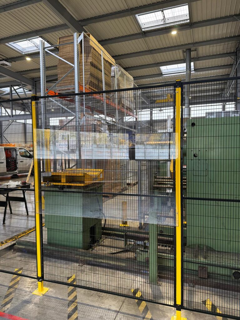Détail d’une cloison grillagée avec protection transparente installée autour d’une machine industrielle