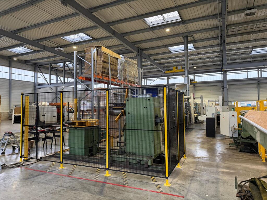 Cloison grillagée installée autour d’une machine industrielle dans un atelier de production pour sécuriser les opérateurs