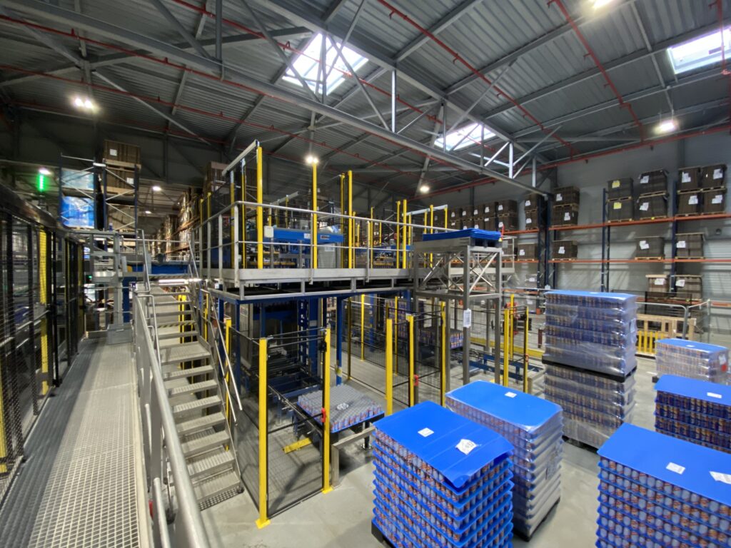 Ligne automatisée sécurisée par cloisons grillagées avec plateforme et mezzanine en environnement logistique