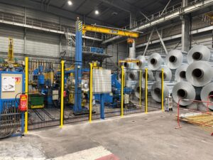 Cloisons grillagées installées autour d’une ligne de production industrielle avec pont roulant et équipements automatisés